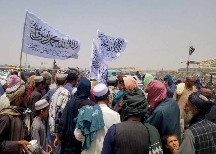 Pessoas com bandeiras do Talibã na fronteira do Afeganistão com o Paquistão, em 16 de agosto de 2021 — Foto: Saeed Ali Achakzai/Reuters
